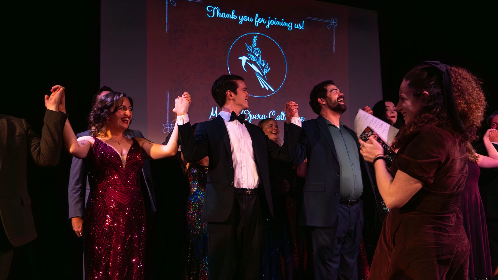 Cast members react with delight as a performer gestures triumphantly during the finale